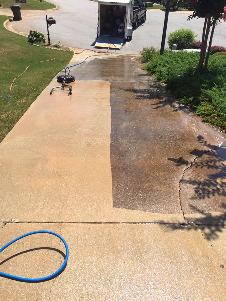 Professional surface cleaner pressure washing a concrete driveway